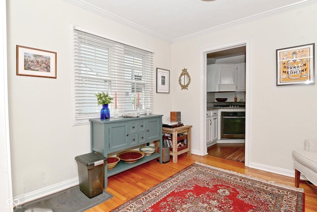 interior space featuring baseboards, ornamental molding, and light wood-style floors