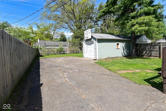 view of patio featuring driveway, an outbuilding, a fenced backyard, and a garage