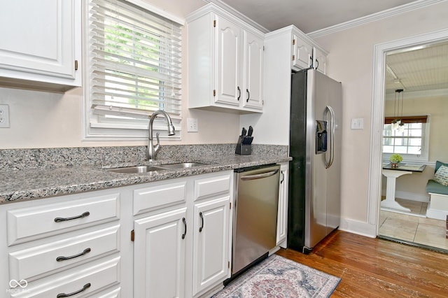 kitchen featuring crown molding, white cabinetry, appliances with stainless steel finishes, and a sink