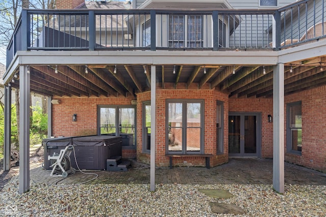 rear view of house featuring a hot tub, a patio area, and brick siding