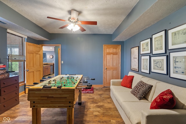 rec room with a ceiling fan, a textured ceiling, and wood finished floors