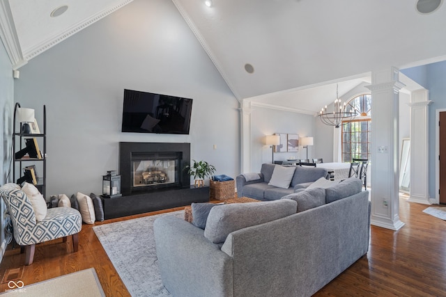 living room with a glass covered fireplace, high vaulted ceiling, ornate columns, a chandelier, and dark wood finished floors