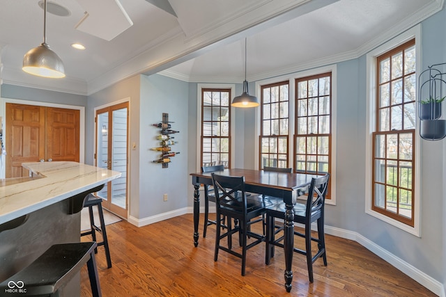 dining room with baseboards, ornamental molding, wood finished floors, and a healthy amount of sunlight