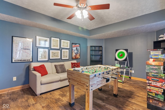 playroom with a textured ceiling, baseboards, and wood finished floors