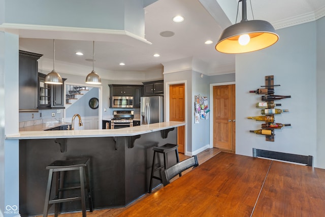 kitchen featuring light countertops, appliances with stainless steel finishes, ornamental molding, and a kitchen bar