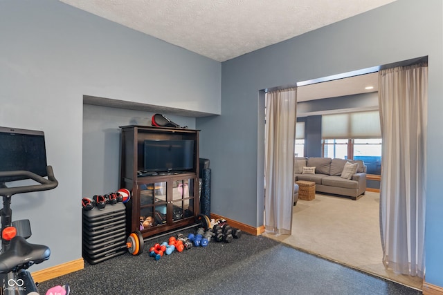 recreation room featuring baseboards, carpet flooring, and a textured ceiling