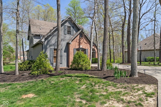 tudor home featuring brick siding, driveway, and a front yard