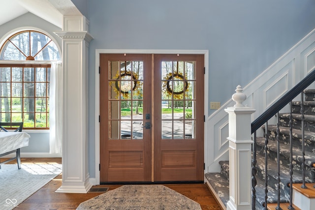 foyer featuring french doors, vaulted ceiling, stairs, ornate columns, and dark wood-type flooring