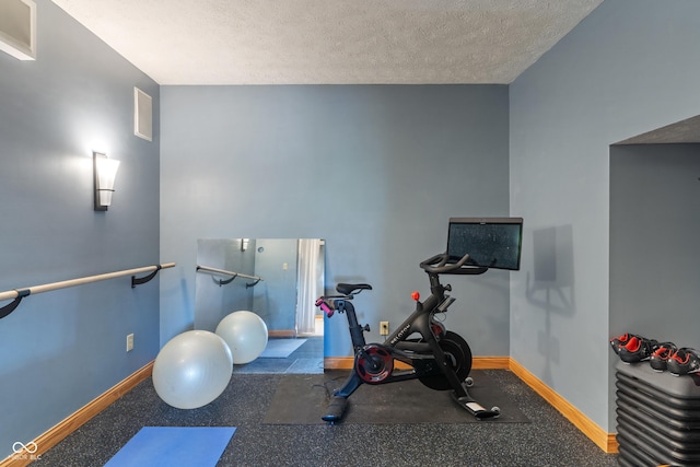 exercise area featuring a textured ceiling and baseboards