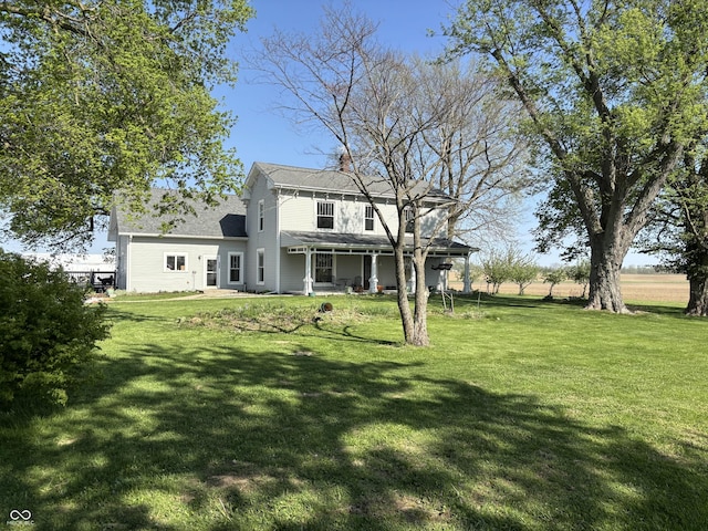 rear view of house featuring a yard, a shingled roof, and a porch