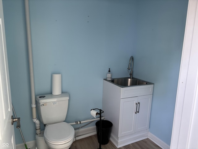 bathroom featuring toilet, baseboards, a sink, and wood finished floors