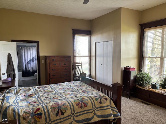 bedroom with a textured ceiling, visible vents, and carpet