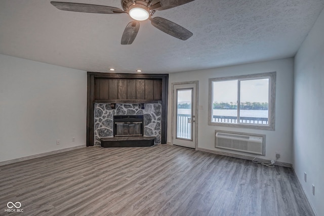 102 Clarendon Dr Unit 506, Noblesville, IN 46062 - unfurnished living room with baseboards, a wall mounted AC, a stone fireplace, and wood finished floors