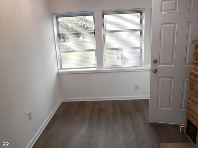 spare room featuring baseboards, dark wood-style flooring, and a fireplace