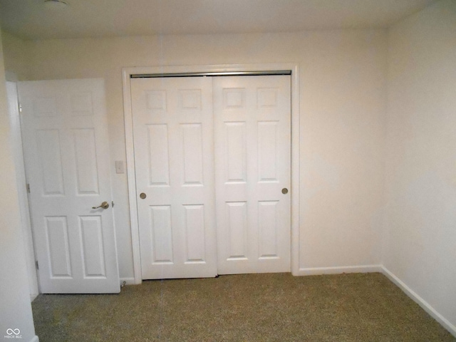 unfurnished bedroom with baseboards, carpet, and a closet