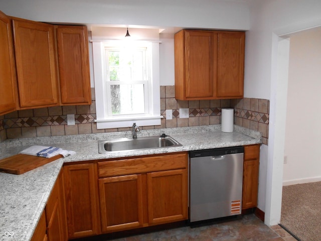kitchen with decorative backsplash, brown cabinetry, stainless steel dishwasher, light stone countertops, and a sink