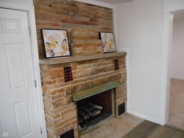 room details with baseboards, a stone fireplace, and wood finished floors
