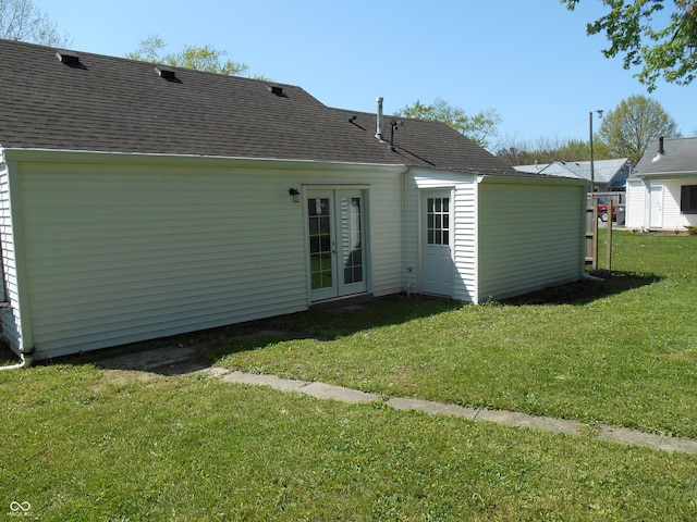 rear view of house with a lawn, roof with shingles, and french doors