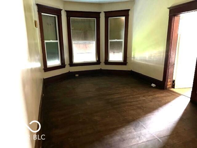 spare room with baseboards and dark wood-style floors