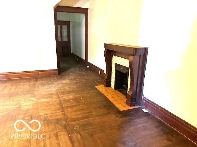 unfurnished living room with a fireplace with flush hearth, baseboards, and wood finished floors