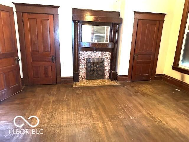 unfurnished living room featuring baseboards, wood finished floors, and a fireplace