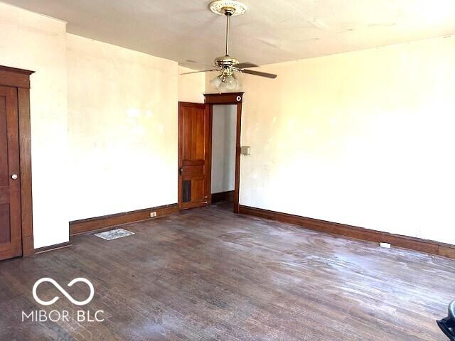 unfurnished room featuring baseboards, dark wood finished floors, and ceiling fan