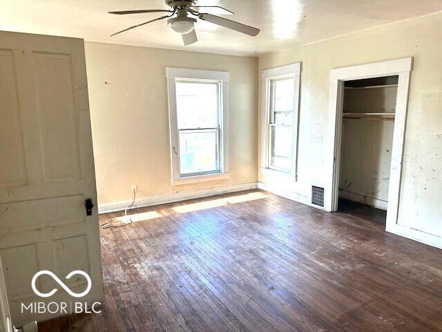 unfurnished bedroom with wood-type flooring, visible vents, a closet, baseboards, and ceiling fan