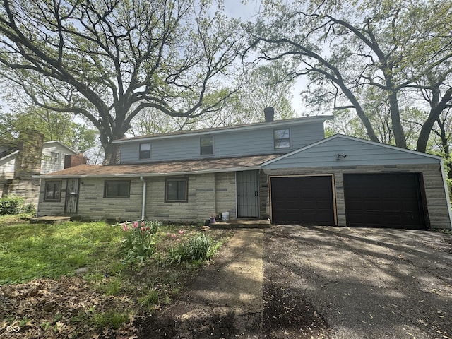 2425 S Lyons Ave, Indianapolis, IN 46241 - view of front of property featuring a chimney, an attached garage, driveway, and stone siding