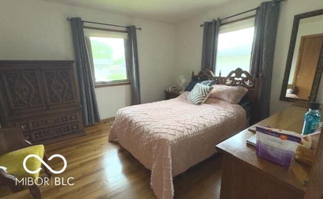 bedroom with wood finished floors and multiple windows