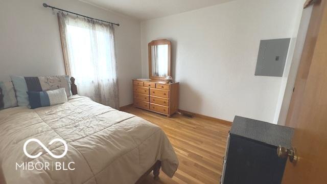 bedroom with electric panel and wood finished floors