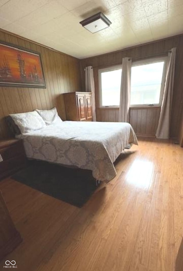 bedroom featuring wood walls, multiple windows, and light wood-type flooring