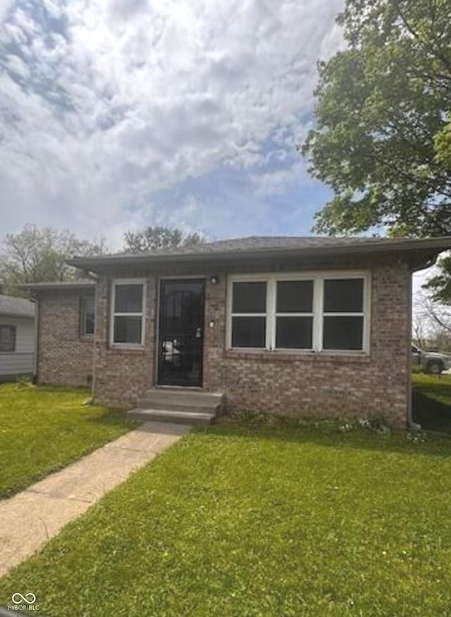 bungalow featuring brick siding and a front lawn