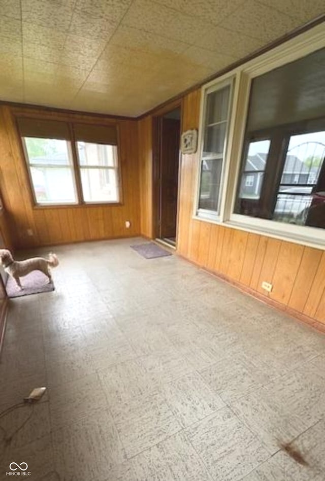 interior space featuring wooden walls, tile patterned floors, and a wealth of natural light