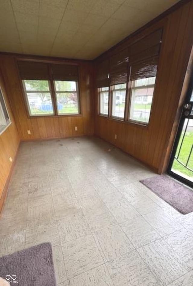 unfurnished room with light floors and wood walls