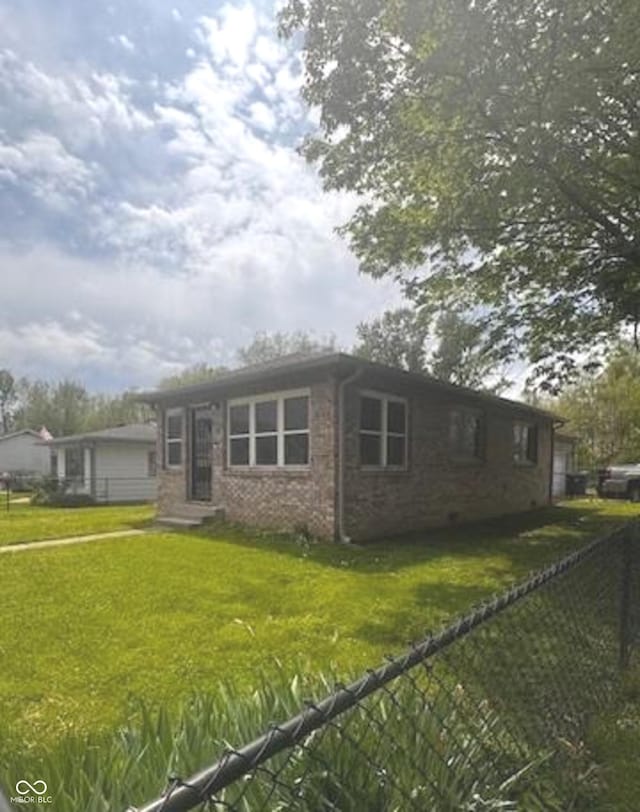 view of front of property with brick siding, fence, and a front yard