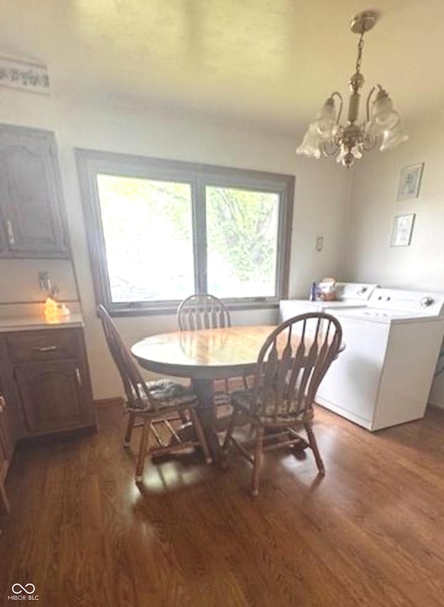 dining area featuring washing machine and clothes dryer, an inviting chandelier, a healthy amount of sunlight, and wood finished floors
