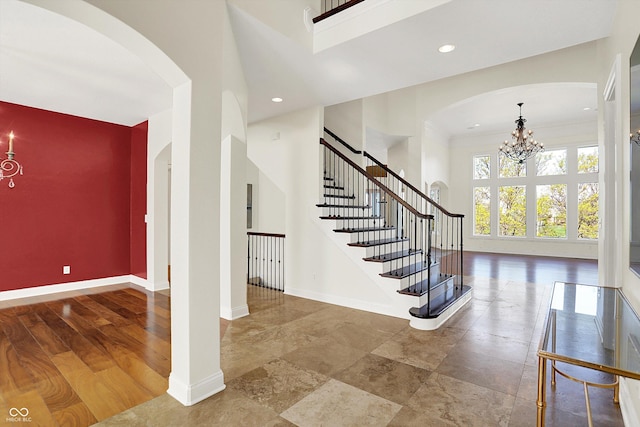 entrance foyer featuring arched walkways, baseboards, an inviting chandelier, and a high ceiling