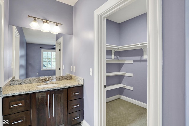 bathroom featuring vanity, baseboards, and a spacious closet