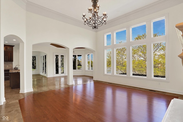 unfurnished living room featuring baseboards, arched walkways, and a towering ceiling