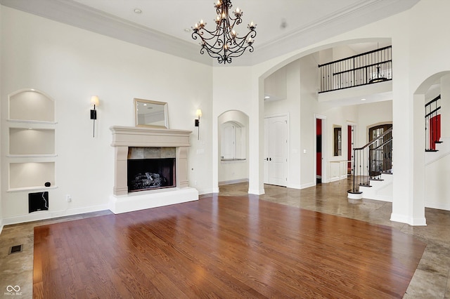 unfurnished living room featuring visible vents, ornamental molding, built in features, and arched walkways