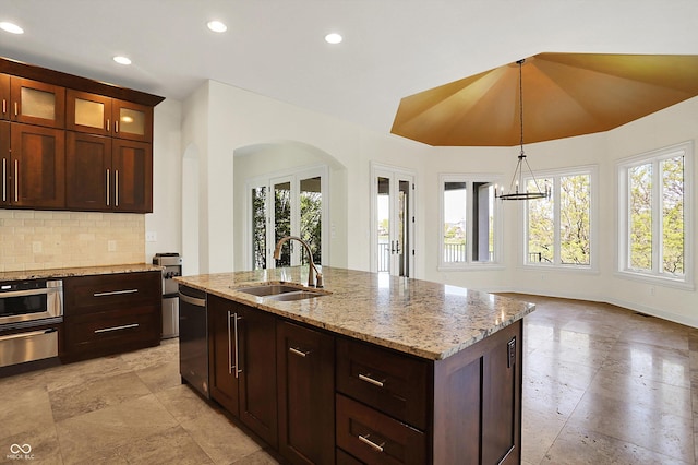 kitchen featuring a sink, arched walkways, a wealth of natural light, dishwashing machine, and a warming drawer