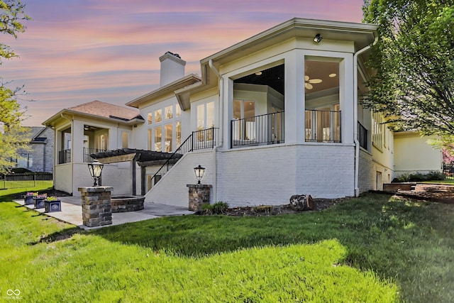view of front of home featuring brick siding, a front yard, a chimney, and a patio