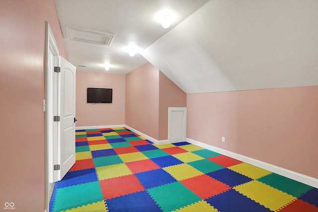 additional living space featuring tile patterned floors, attic access, baseboards, lofted ceiling, and visible vents