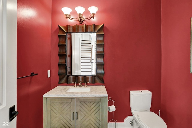 bathroom featuring vanity, toilet, and a notable chandelier