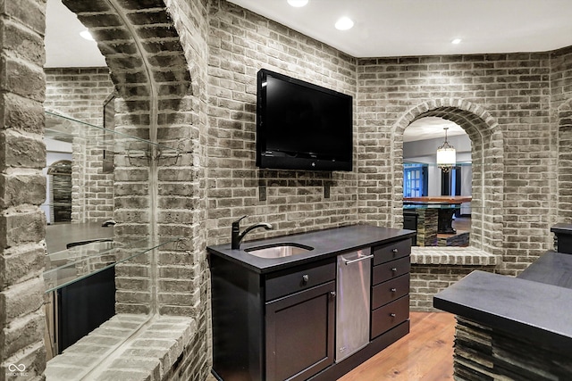 interior space with a sink, arched walkways, brick wall, and wood finished floors