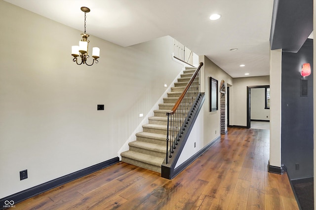 staircase with wood-type flooring, recessed lighting, baseboards, and a notable chandelier