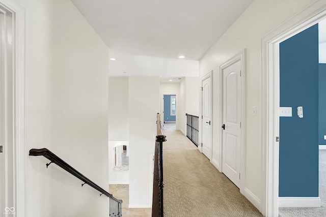 corridor with baseboards, light carpet, and an upstairs landing