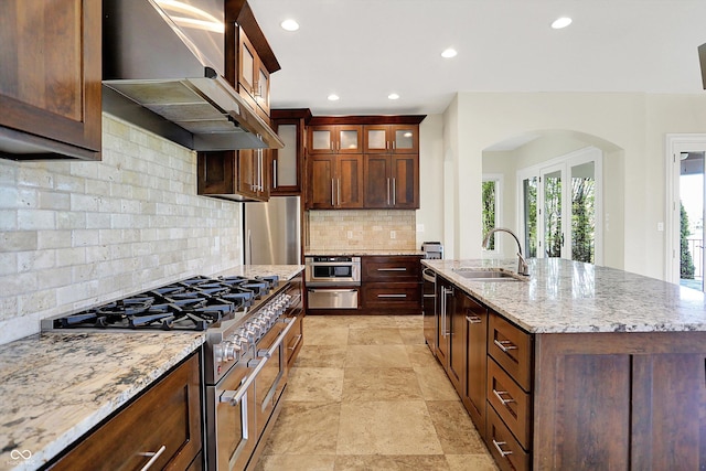 kitchen with range hood, recessed lighting, tasteful backsplash, a sink, and stainless steel appliances