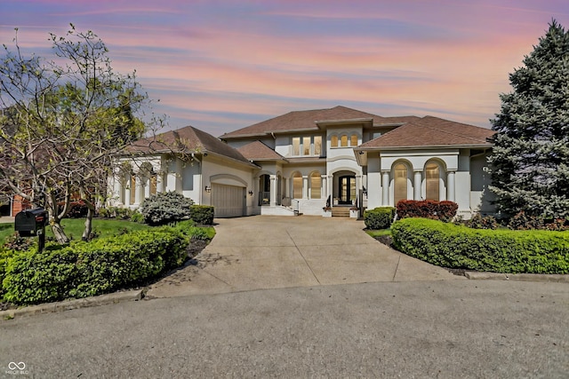 mediterranean / spanish-style house featuring concrete driveway, stucco siding, an attached garage, and roof with shingles