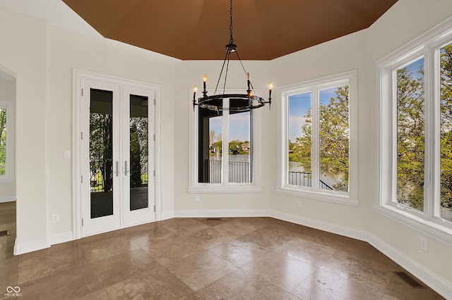 unfurnished dining area featuring an inviting chandelier, a healthy amount of sunlight, french doors, and visible vents